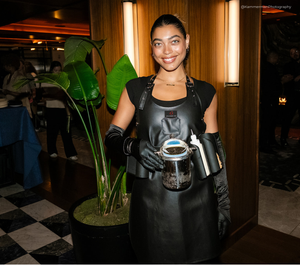 Oysters XO Une « Caviar Girl » vêtue d'un tablier en cuir noir, tenant une cuillère à caviar réfrigérée lors d'un événement